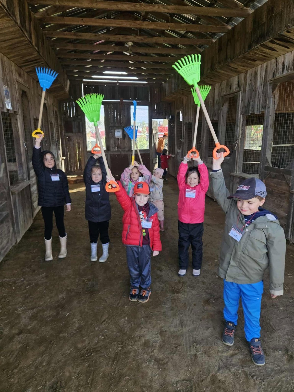 Des petits fermiers fiers, râteaux levés dans la grange