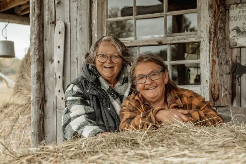Raymonde Cossette et Chantal Héroux, propriétaires de la Ferme-refuge du Boisé, souriantes devant une grange en bois